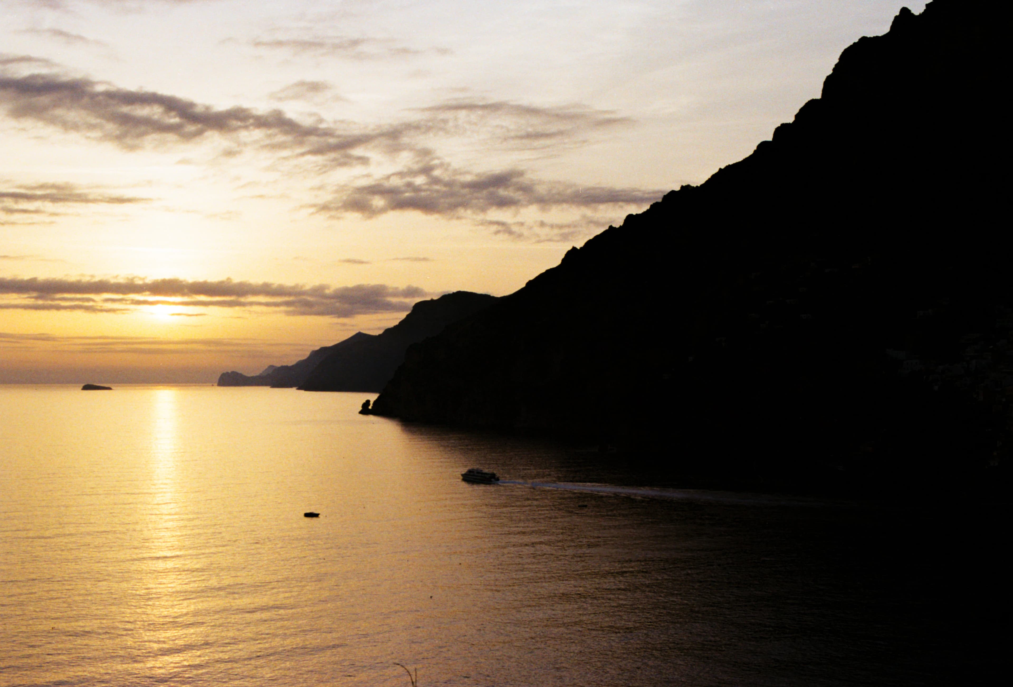 Golden sunset over the calm ocean with mountains.
