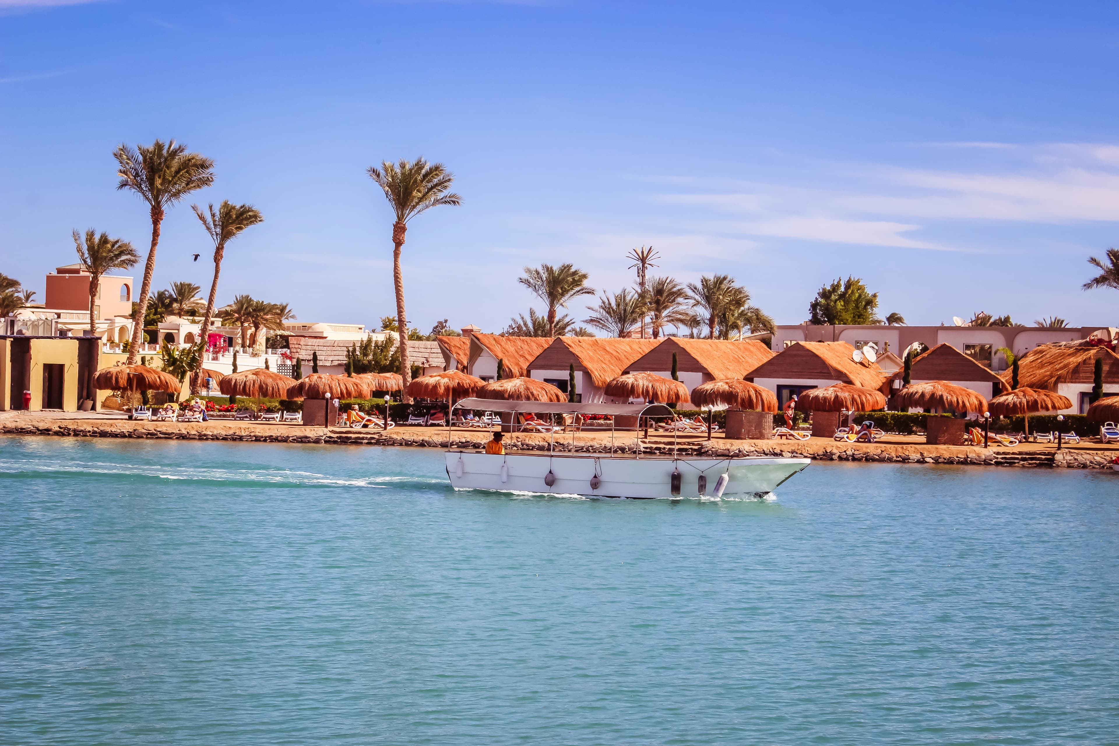 A boat traveling down a river next to a beach
