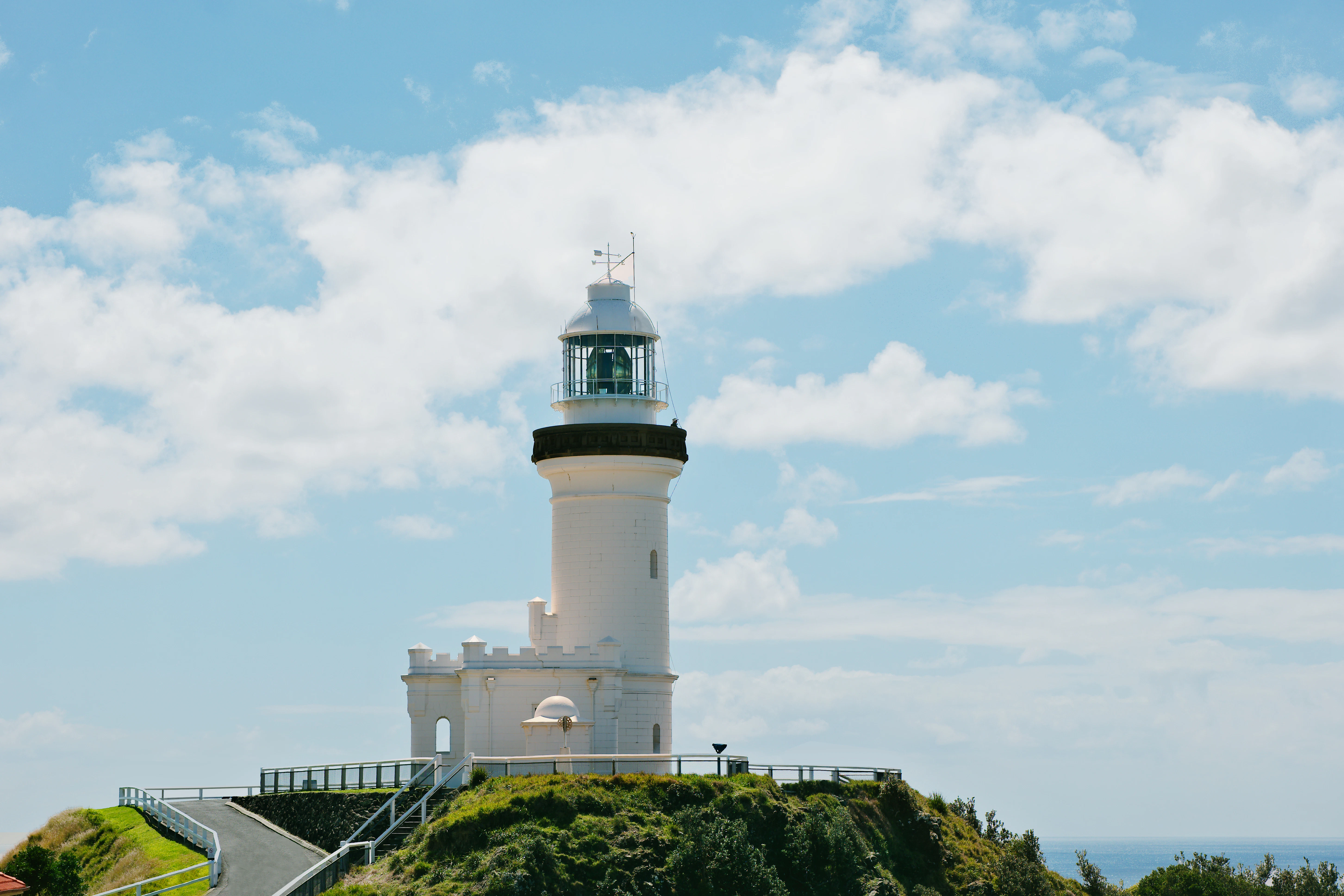 White lighthouse on a grassy hill under blue sky