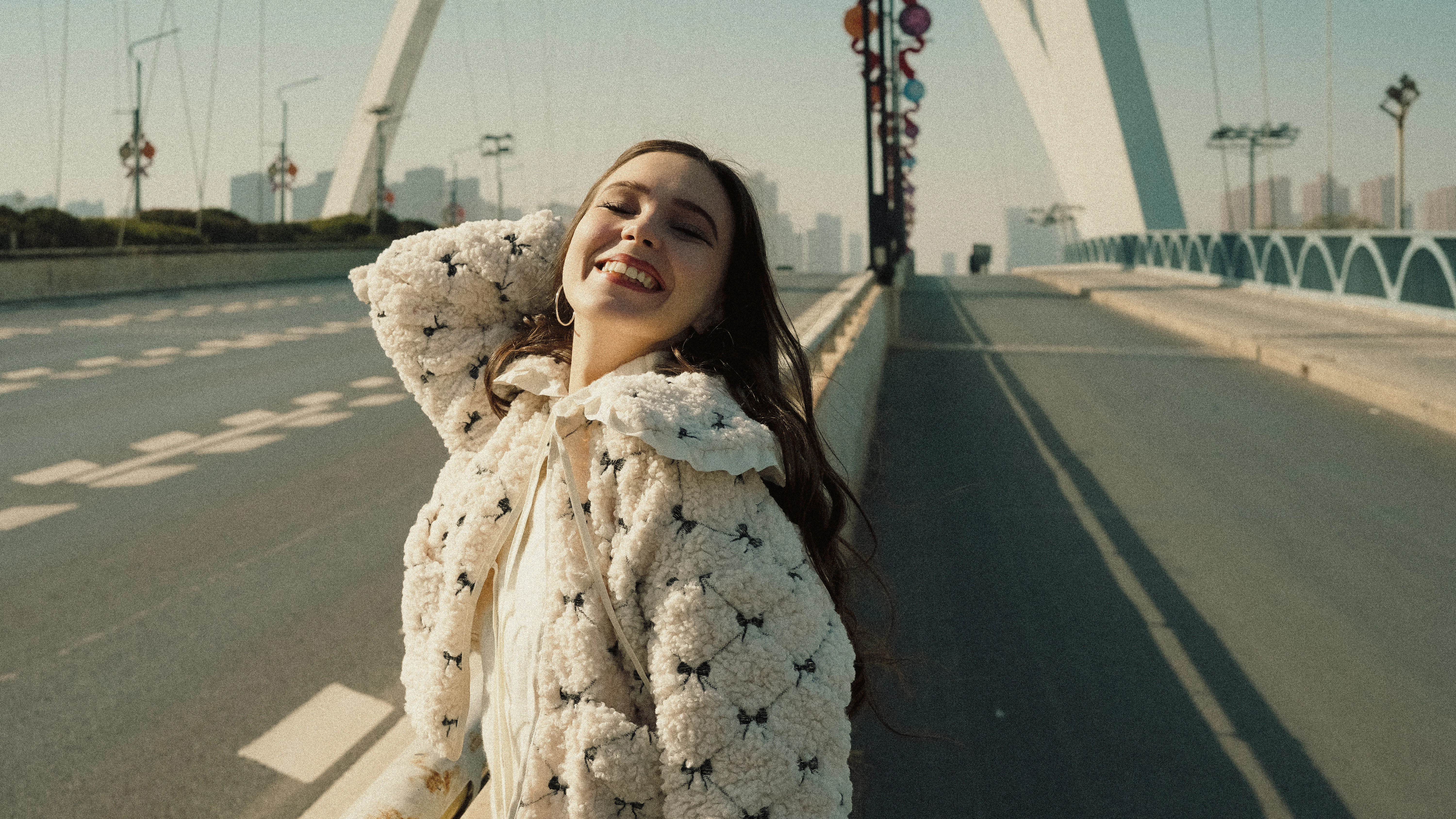 A smiling woman stands on a bridge road