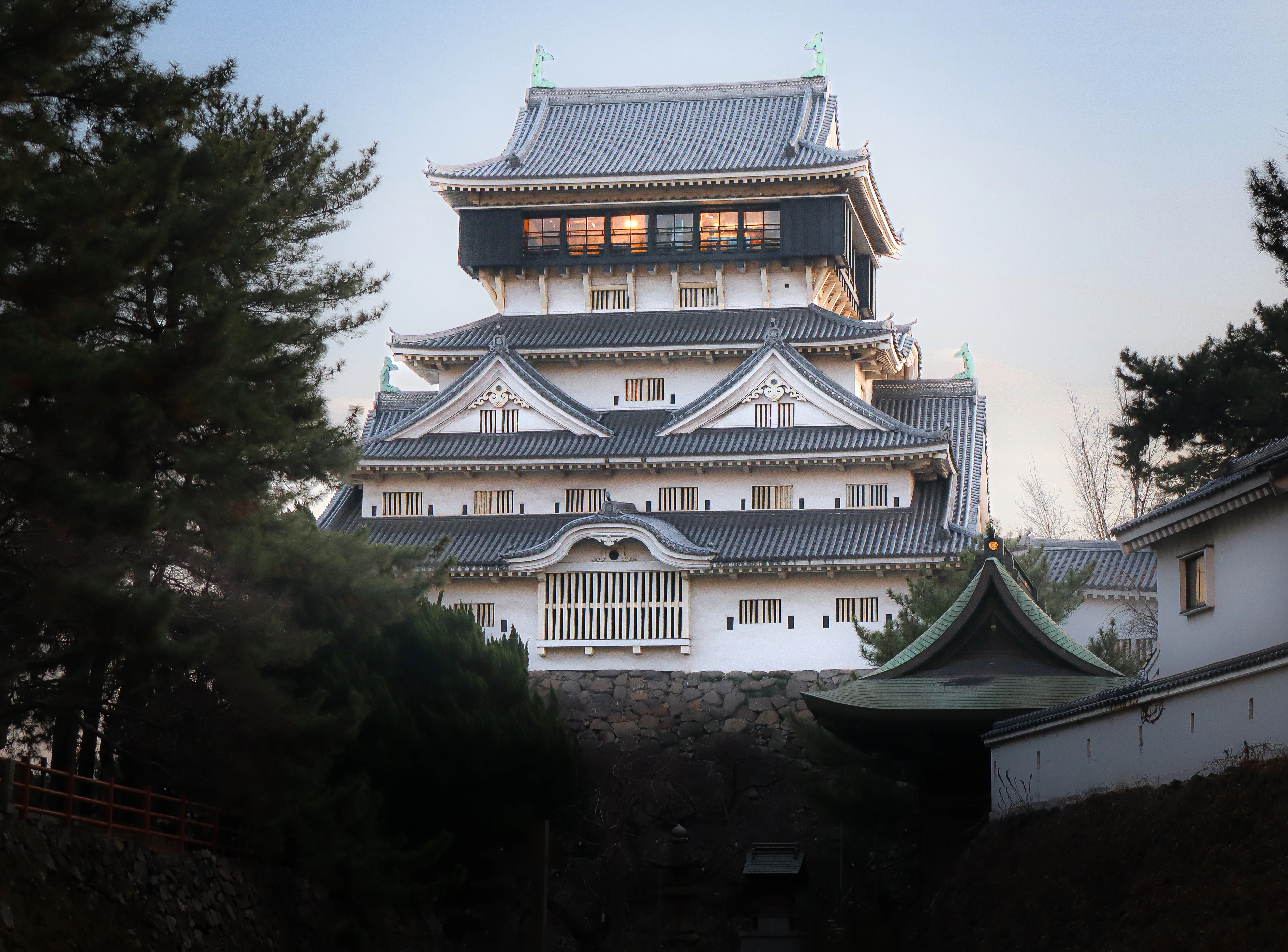 A japanese castle with intricate rooftops and dark trees.