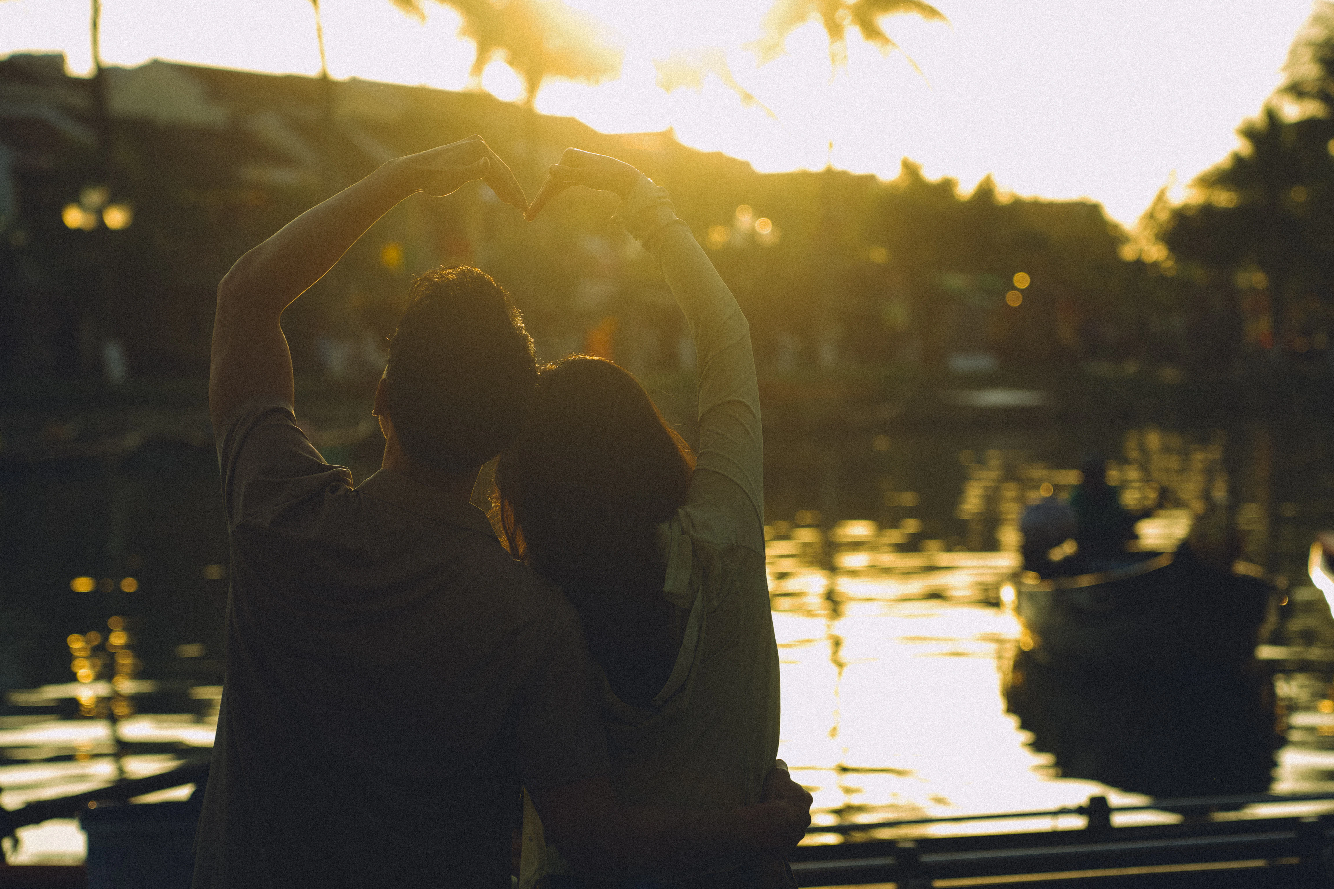 Couple forms heart shape with hands at sunset