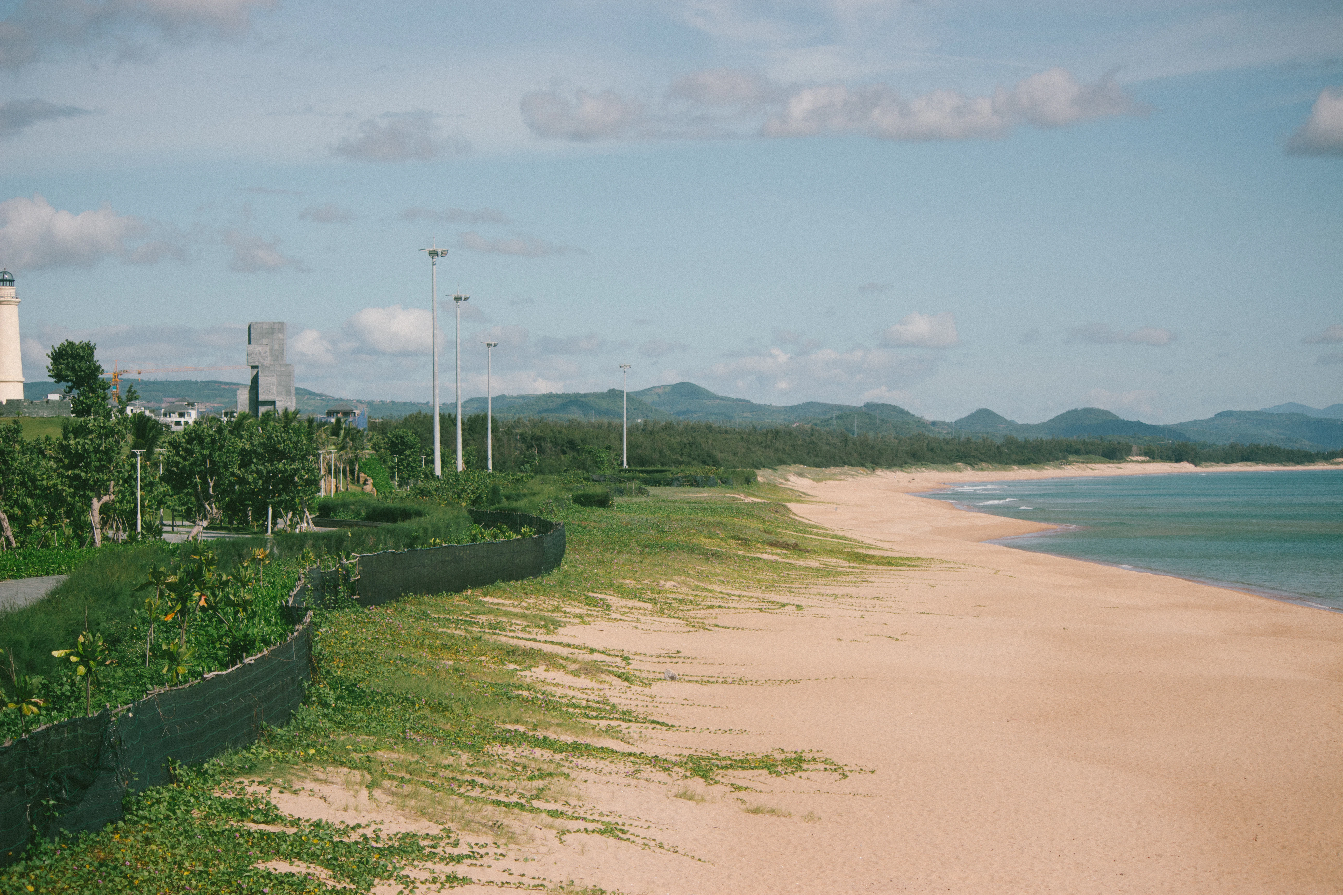 a sandy beach with a light house in the distance