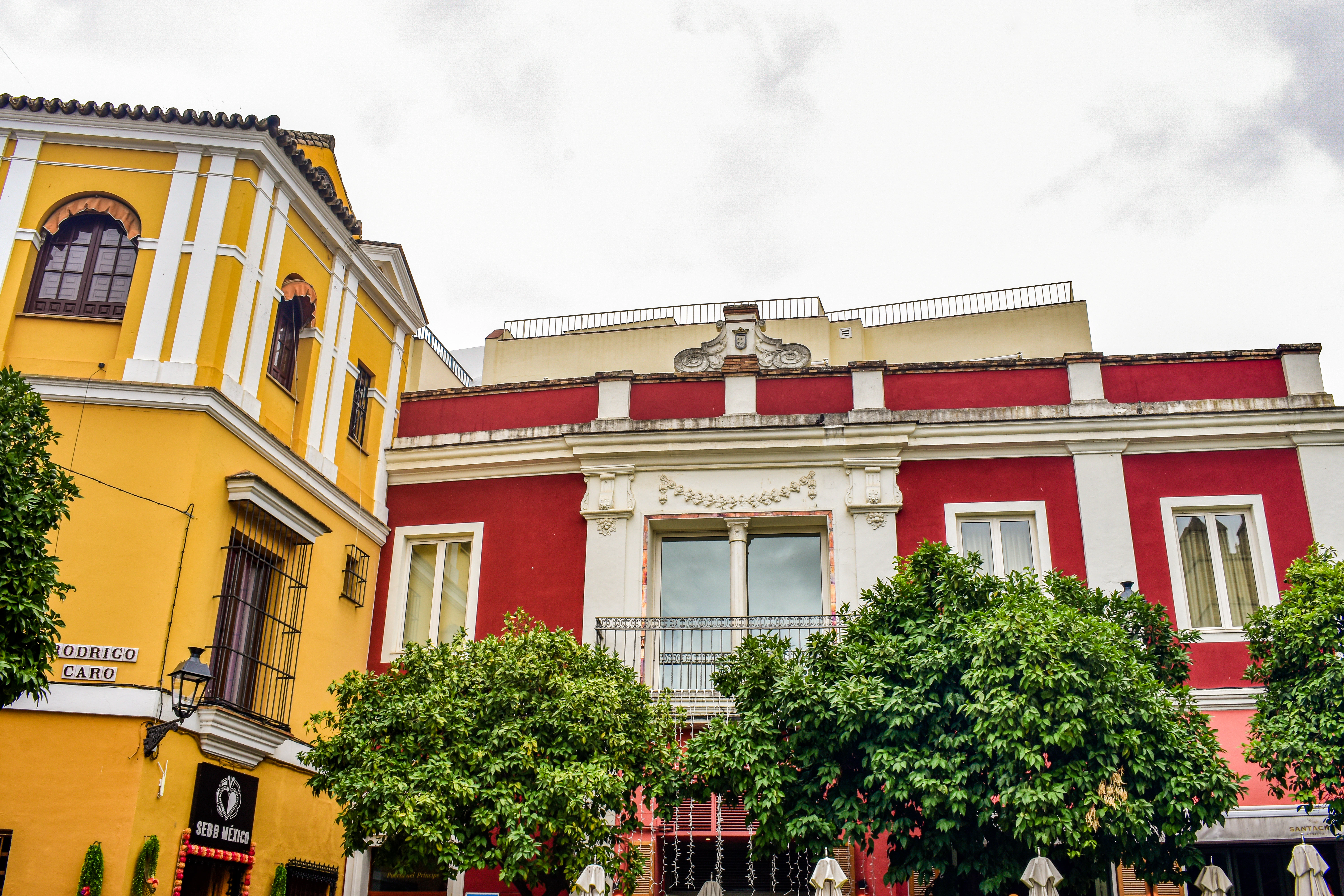 A yellow and red building with trees in front of it
