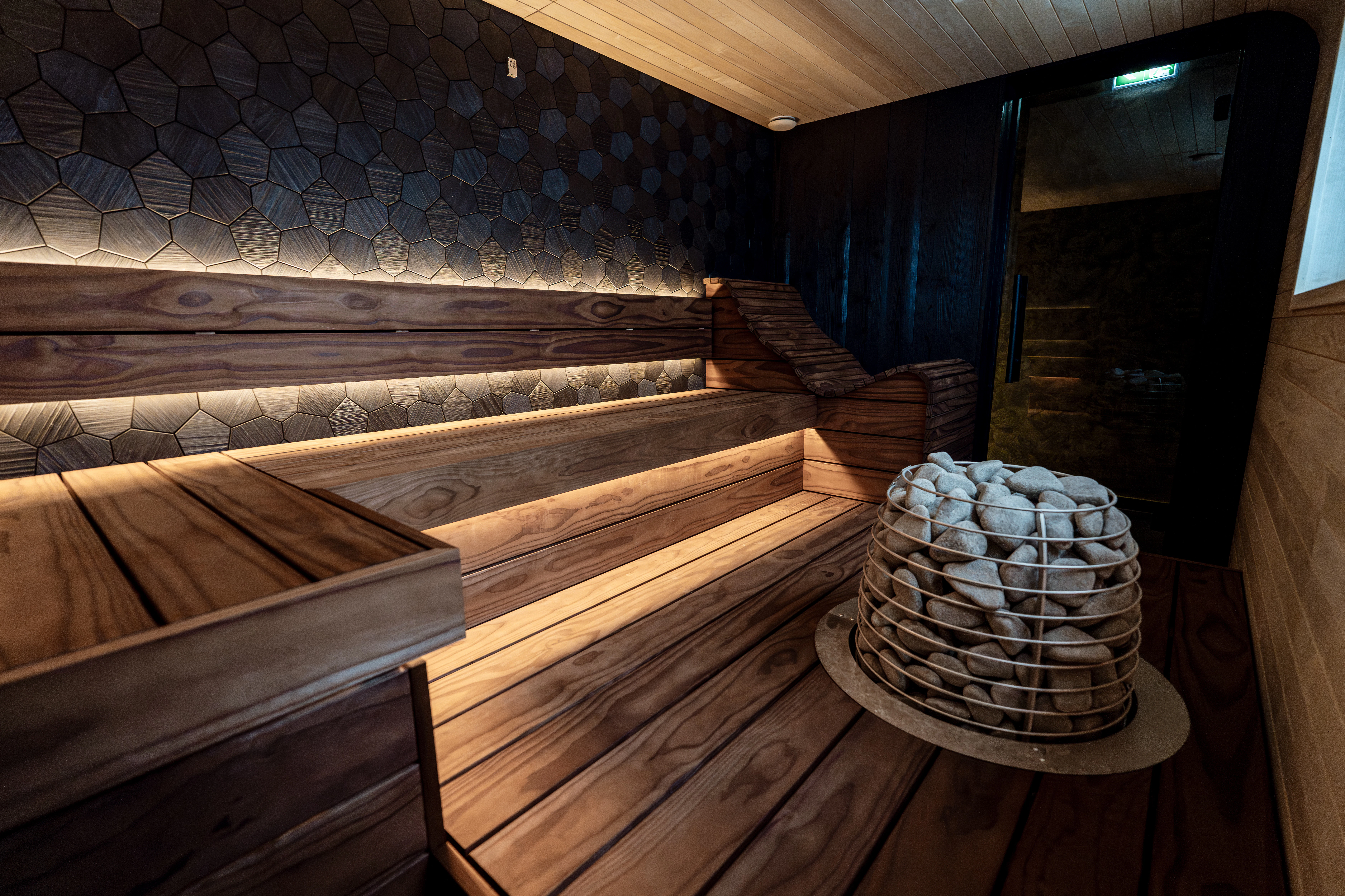 A modern sauna with wooden benches and hot stones