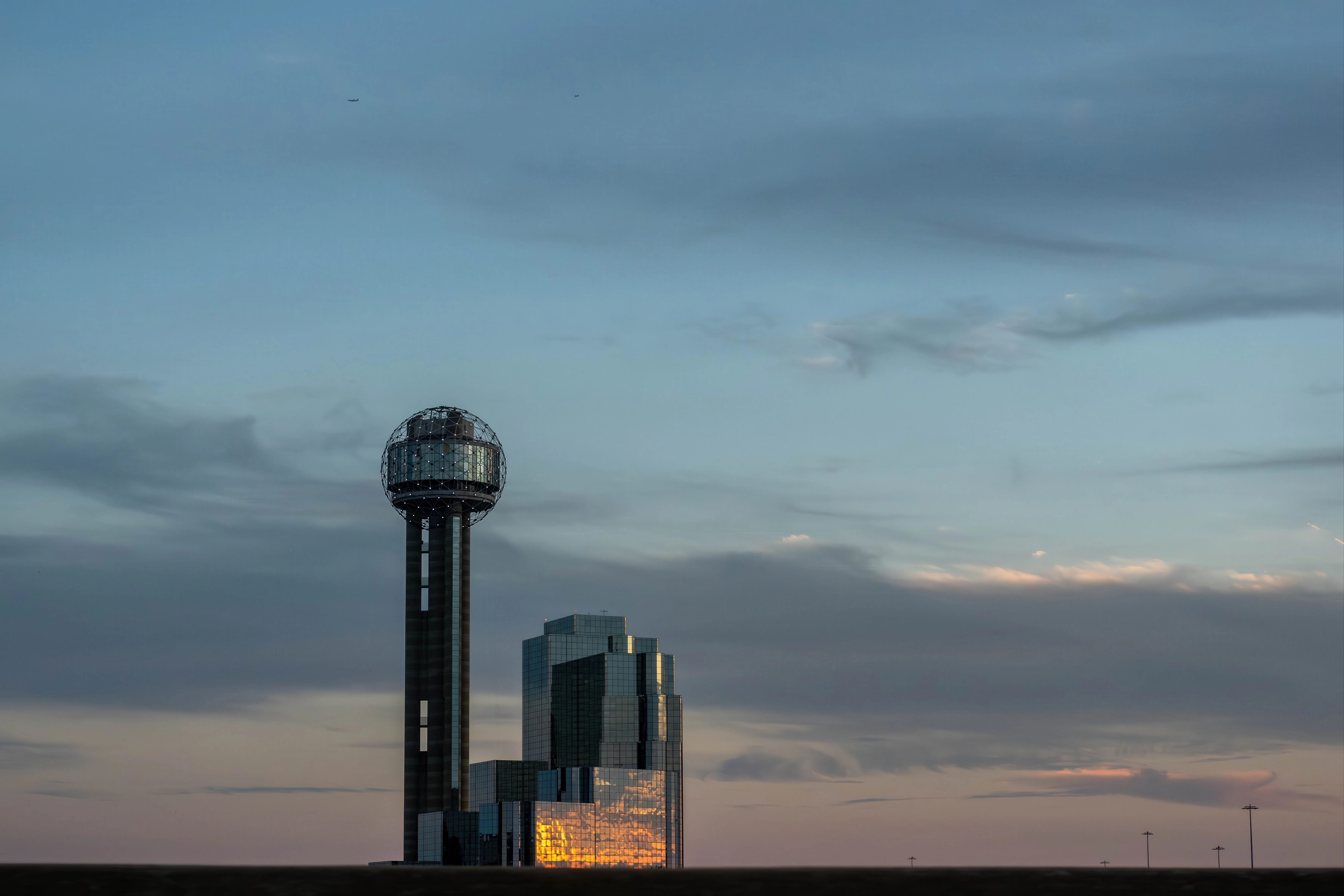 Modern buildings with a tall observation tower at sunset.