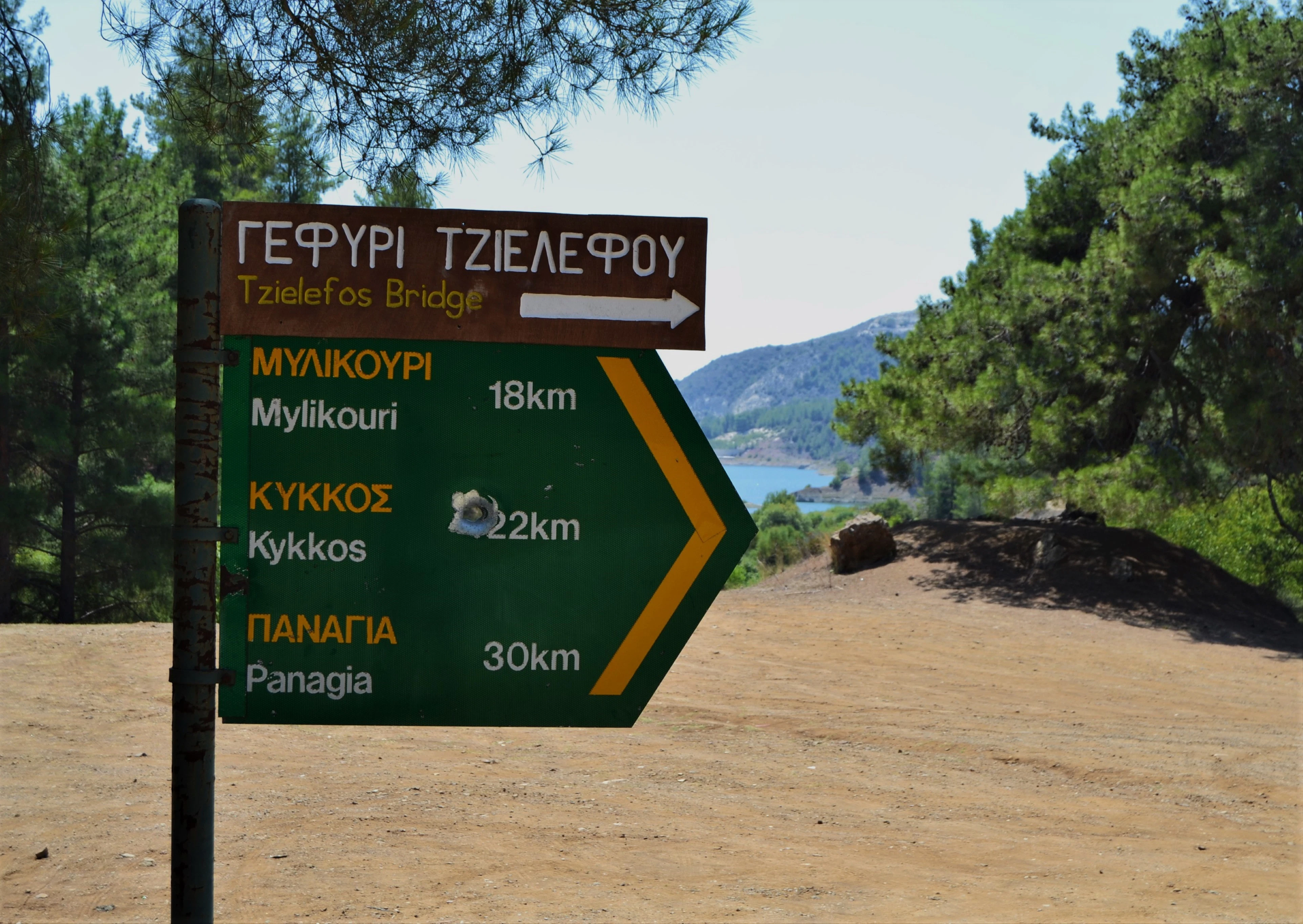 A sign that is on the side of a dirt road