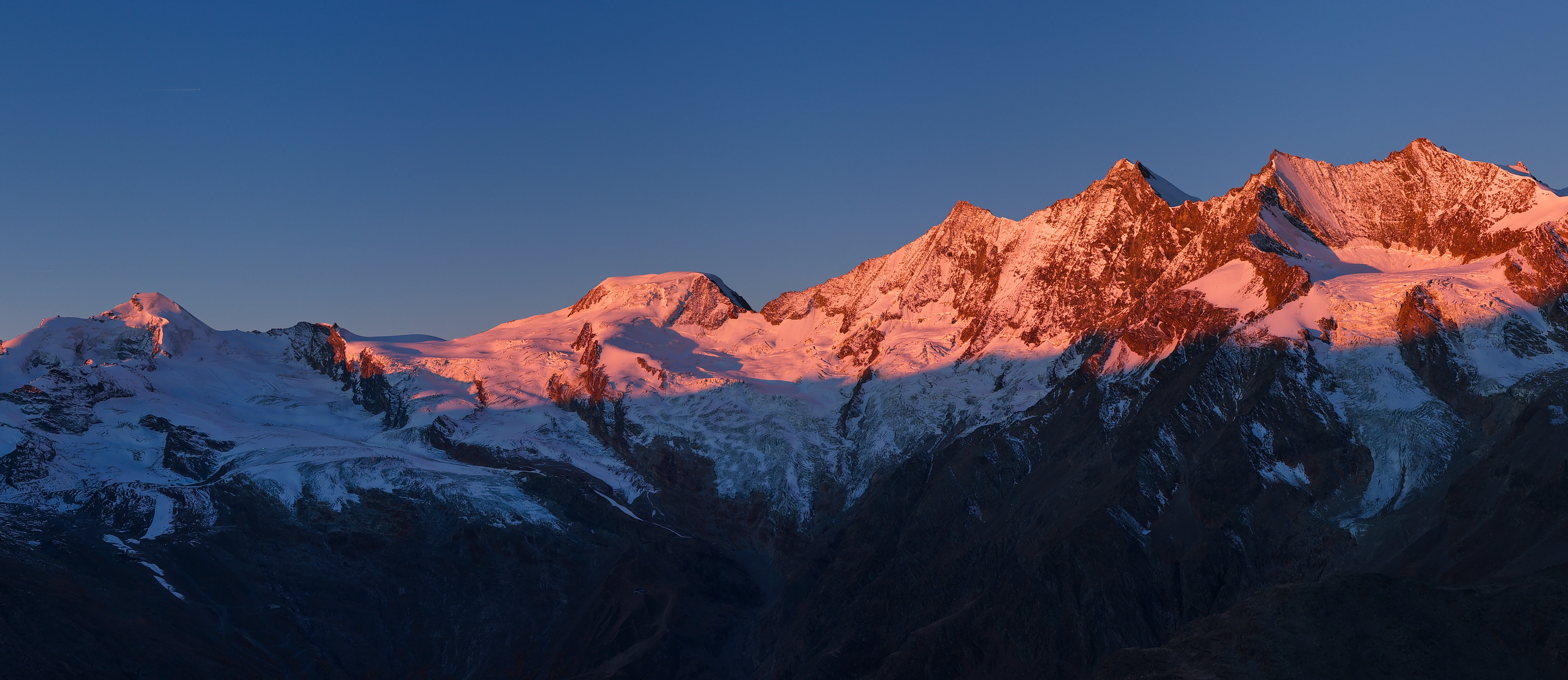 Snow-capped mountains bathed in pink sunset light.
