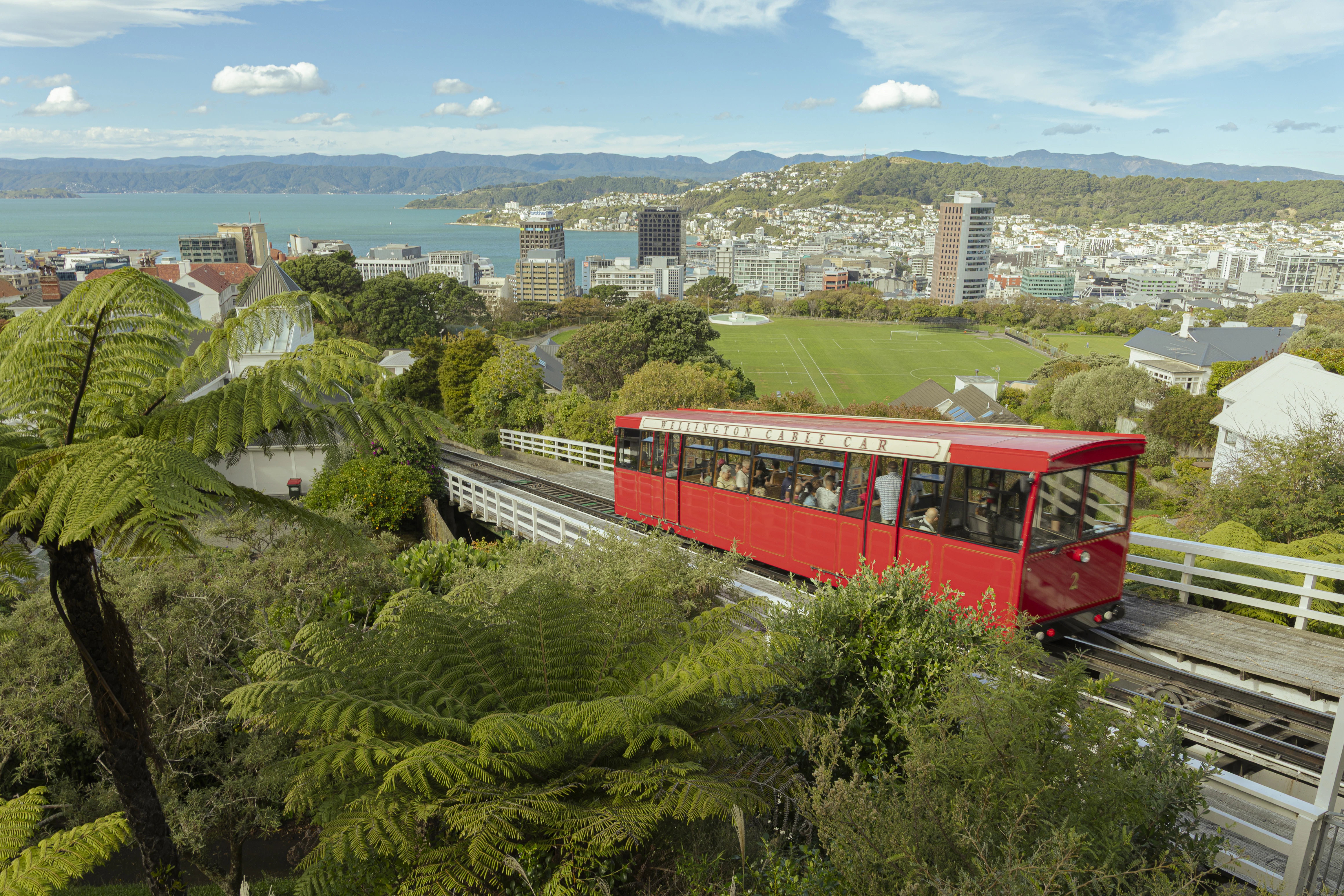 A red cable car travels through a scenic city.