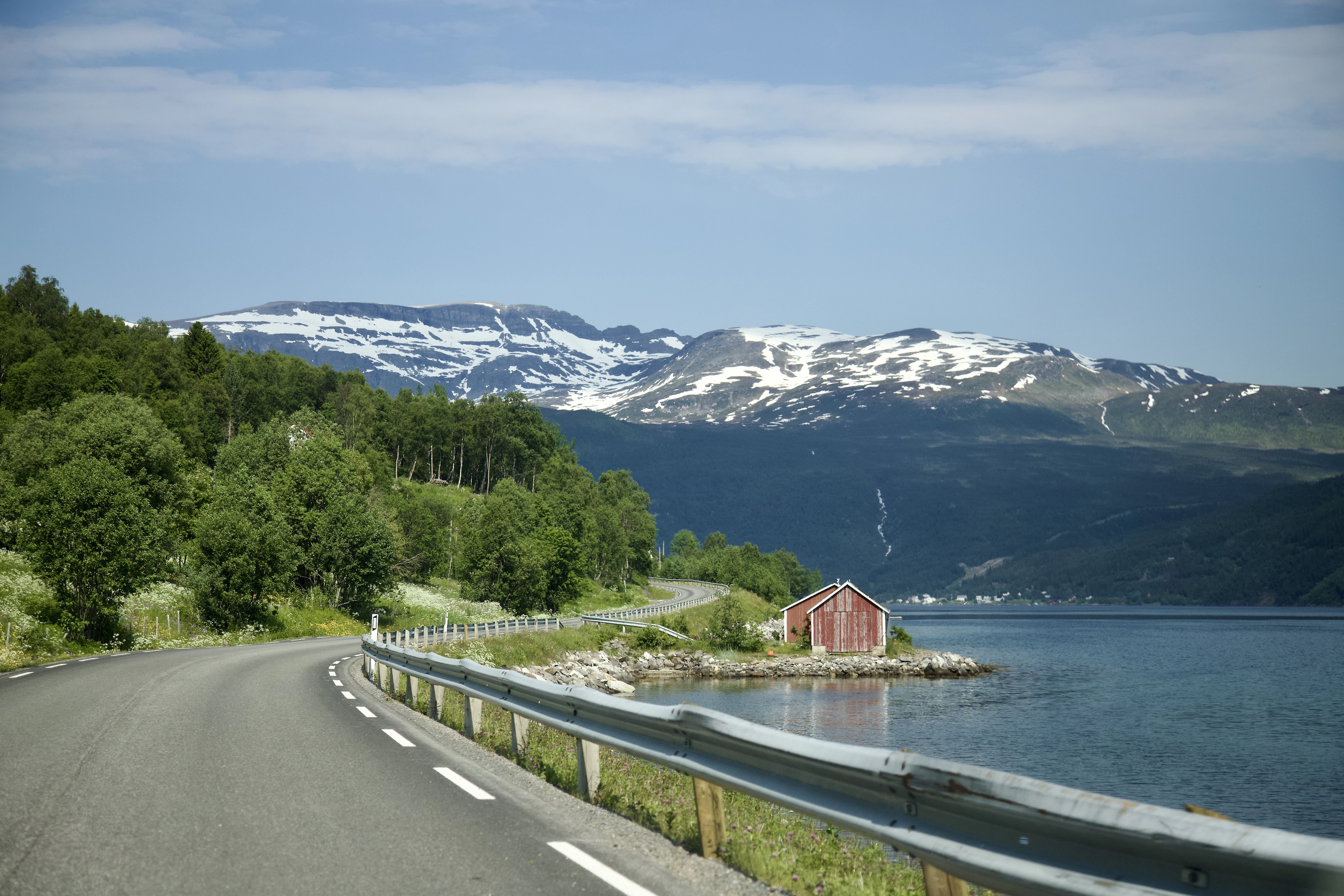 a road next to a body of water with mountains in the background