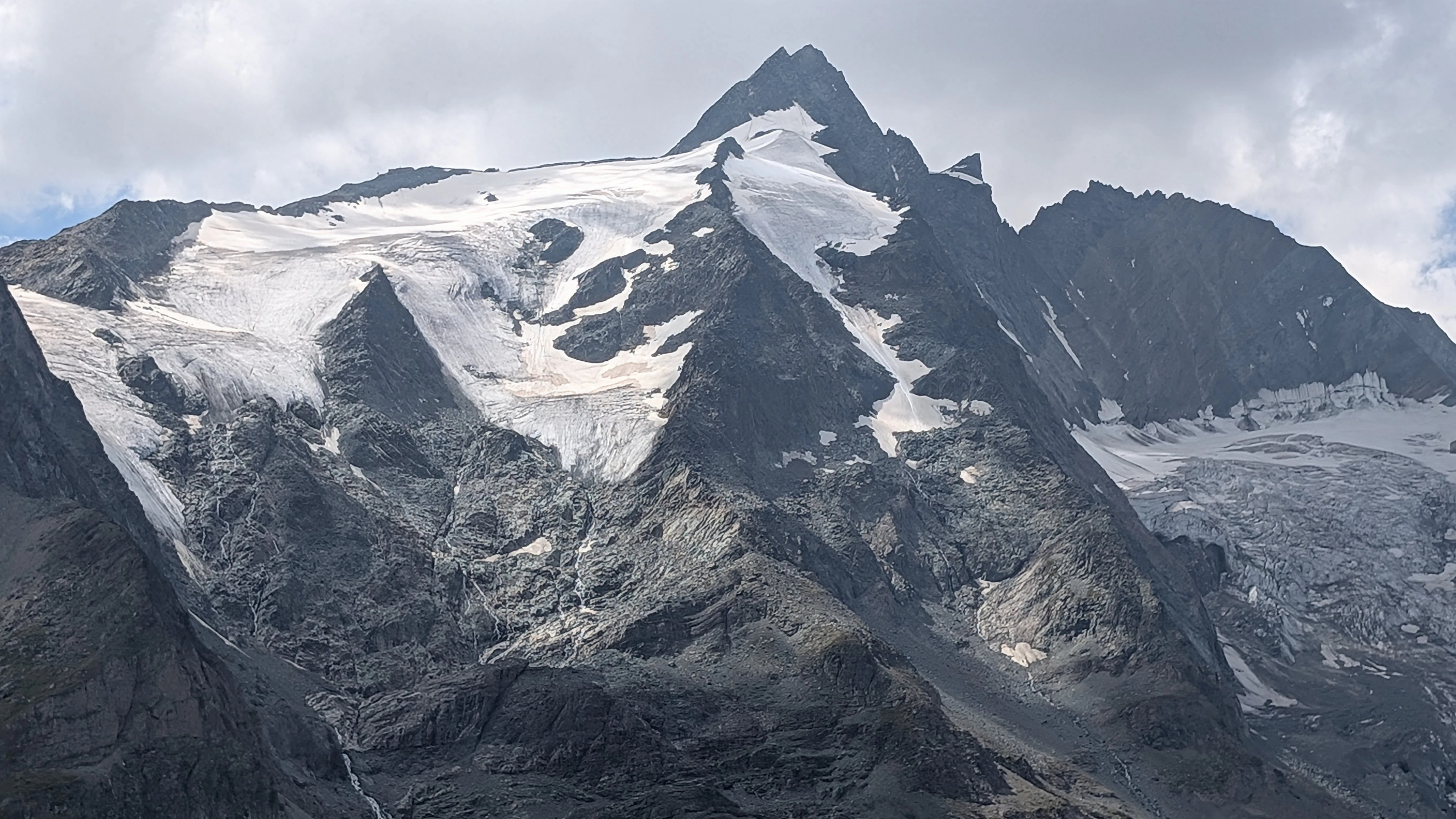 Snow-capped mountain peaks under a cloudy sky