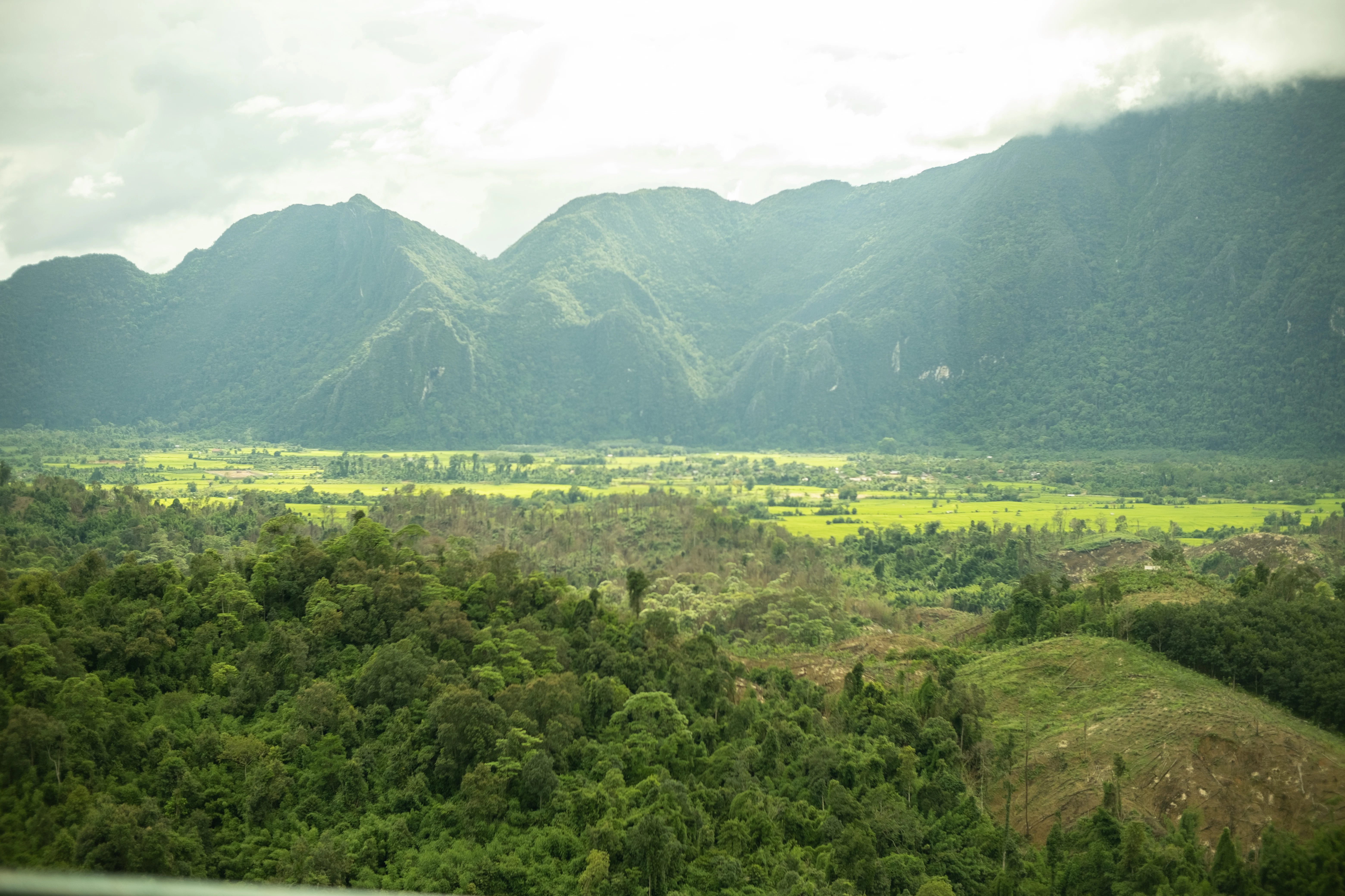 Mountains overlook a lush valley and greenery.