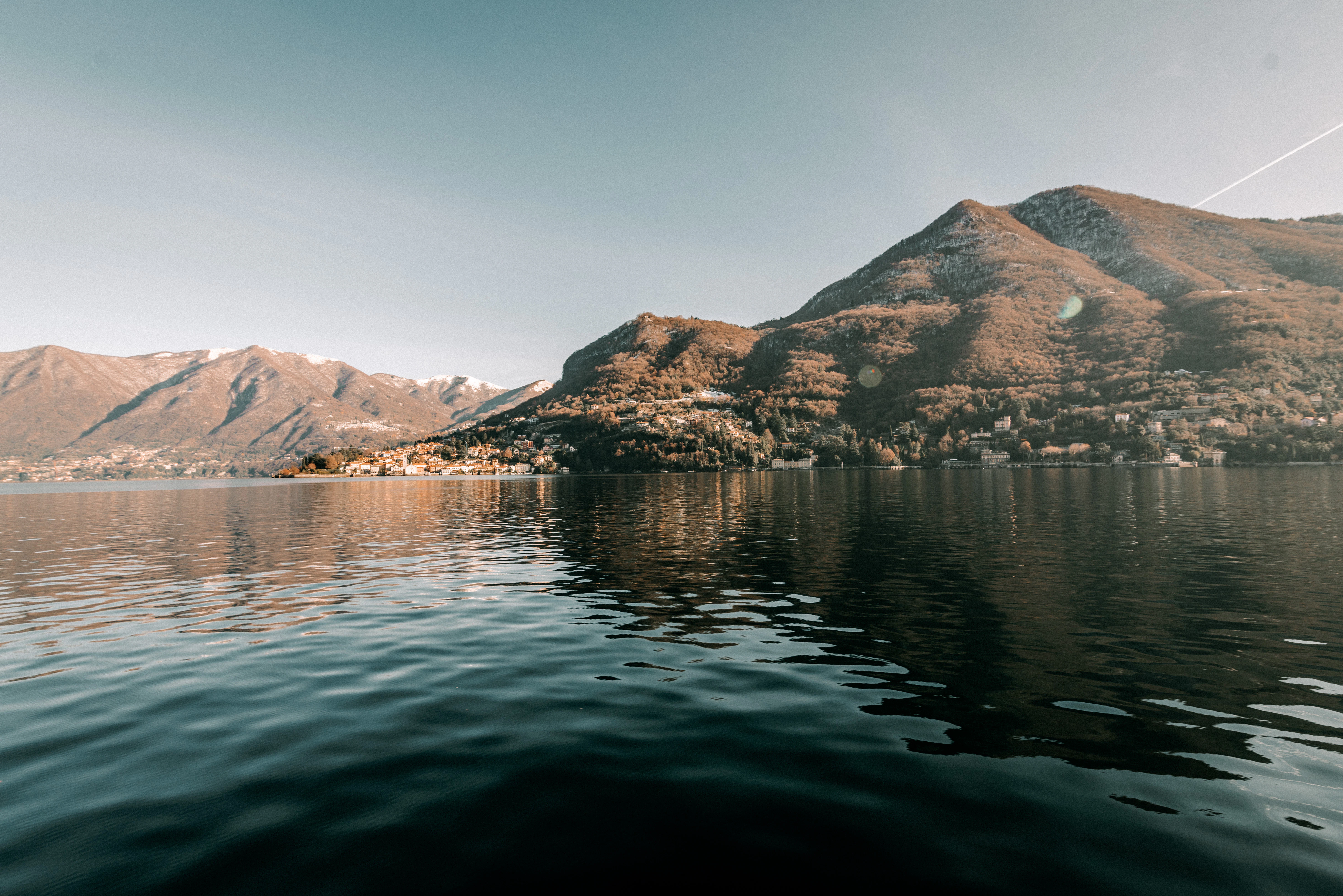 Calm lake reflecting mountains and a small town.