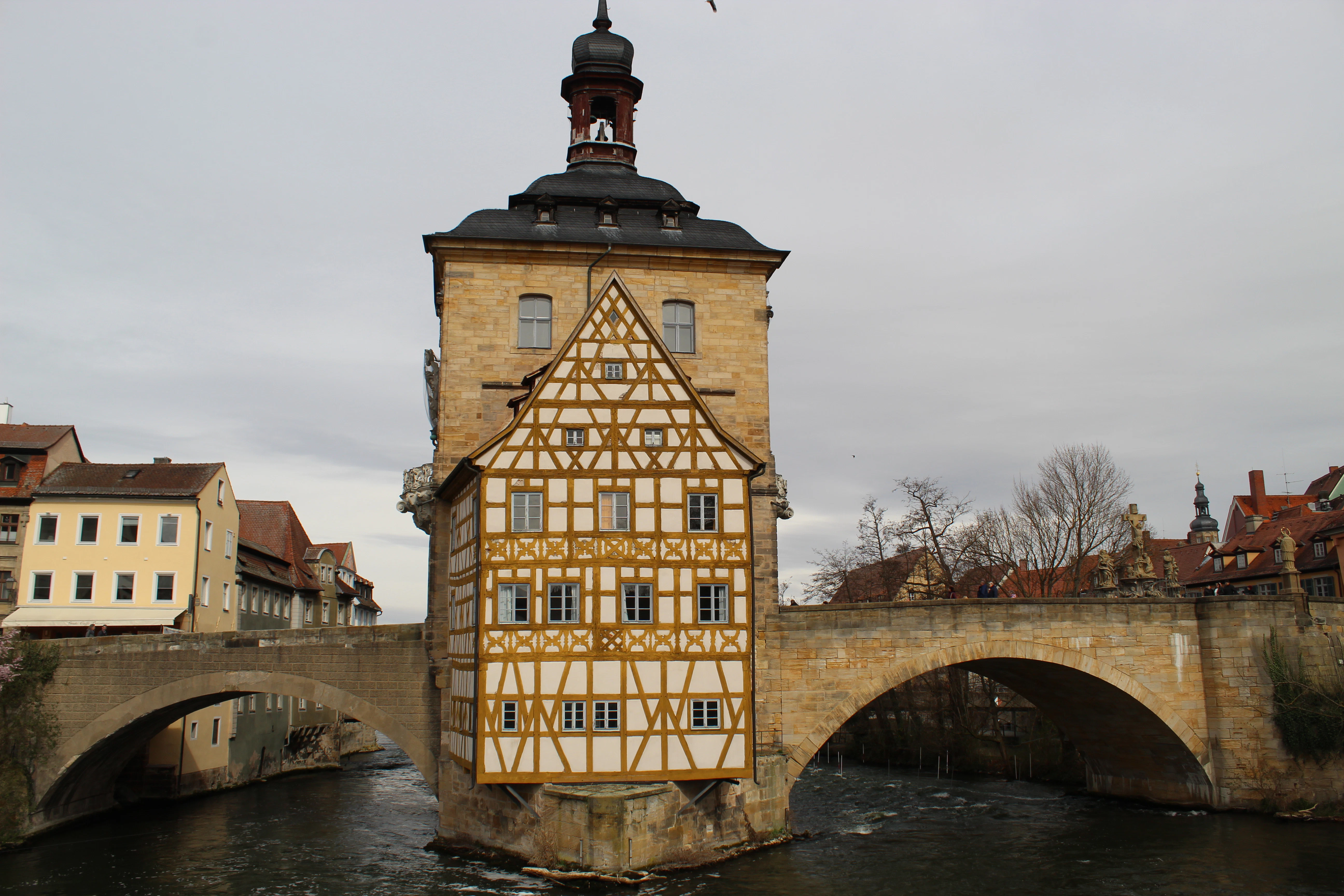 The old town hall sits on a bridge over the river.