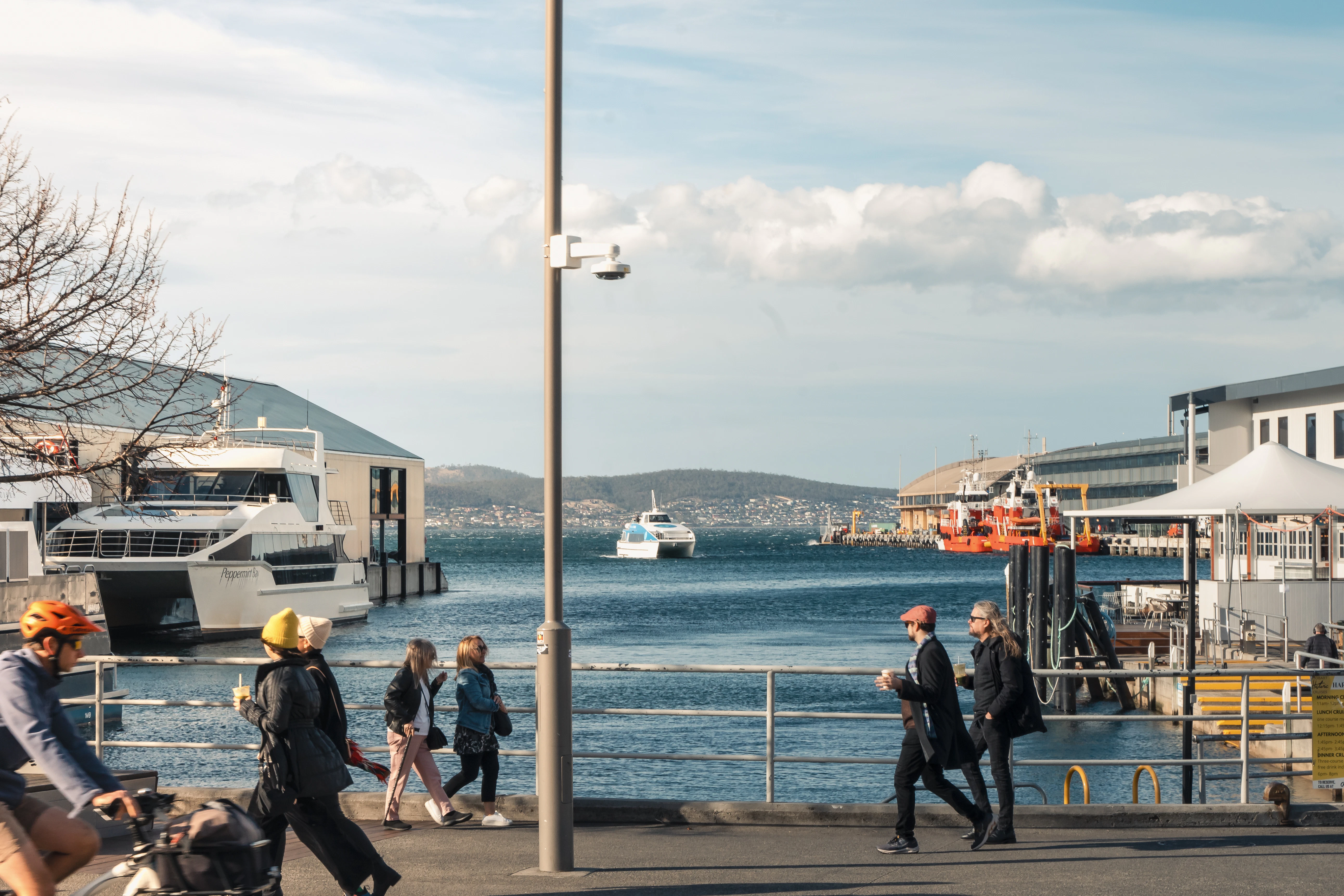 a group of people walking down a street next to a body of water