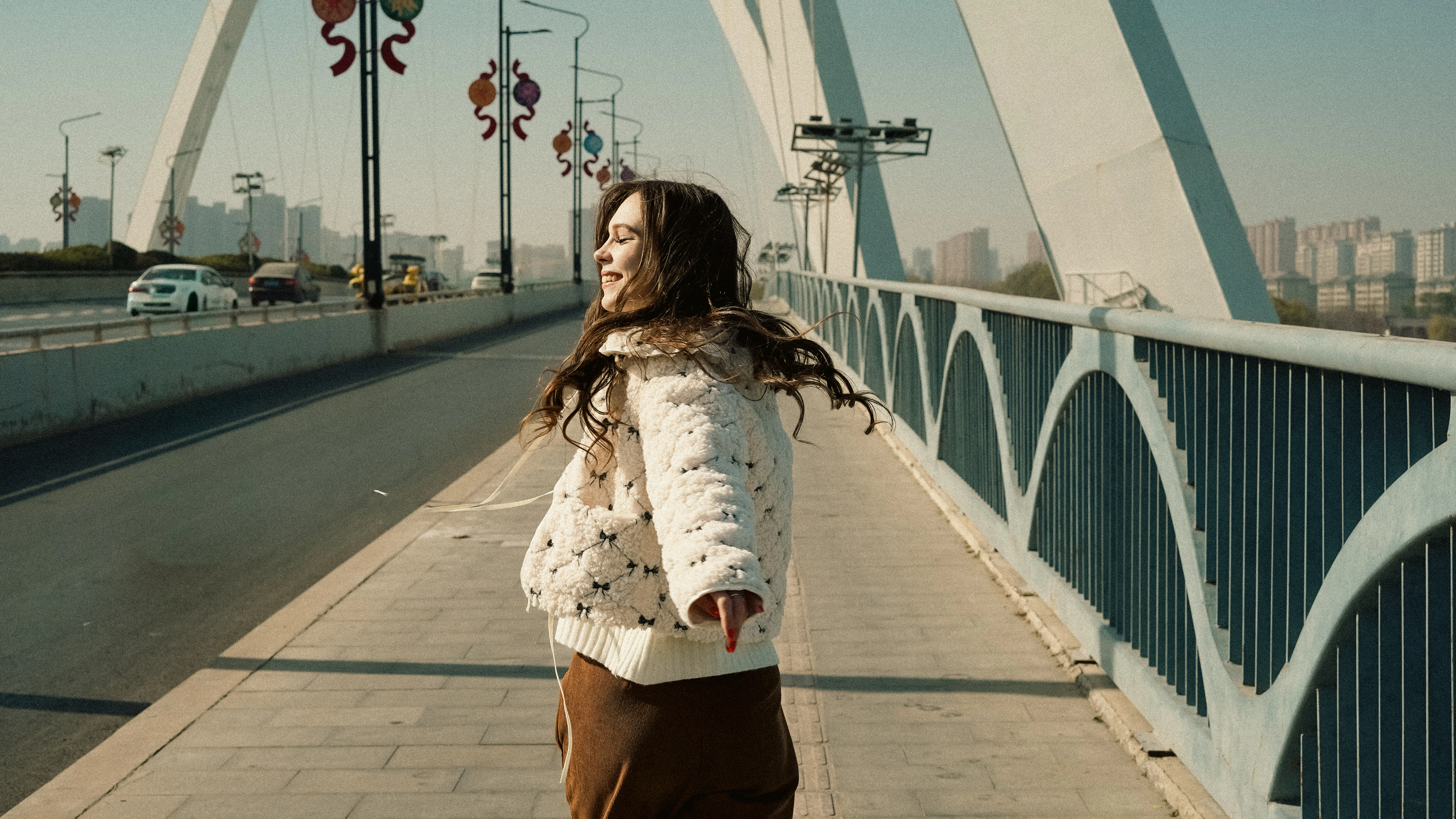 Young woman walking on a bridge with city skyline