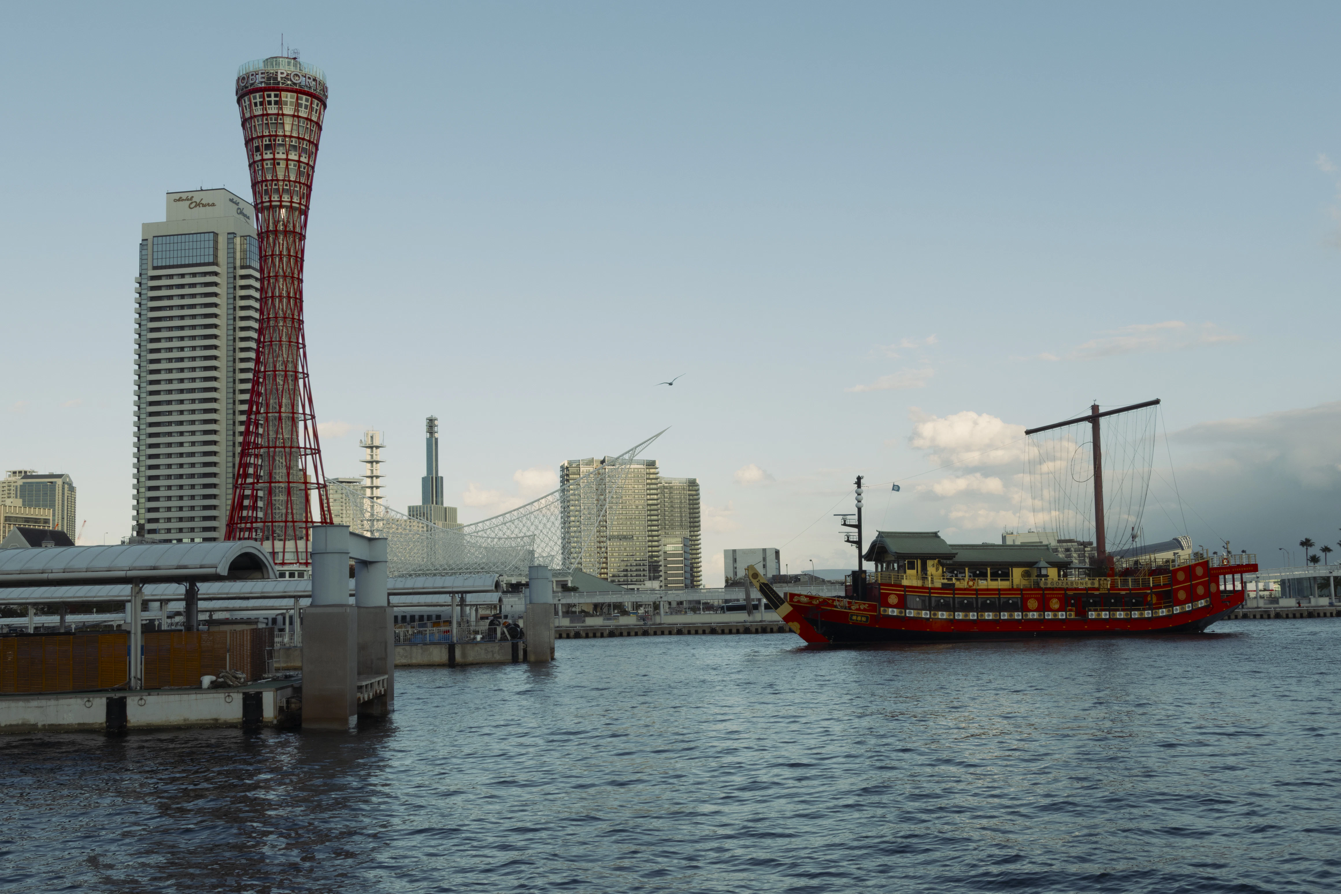 A traditional boat sails in a bustling harbor.