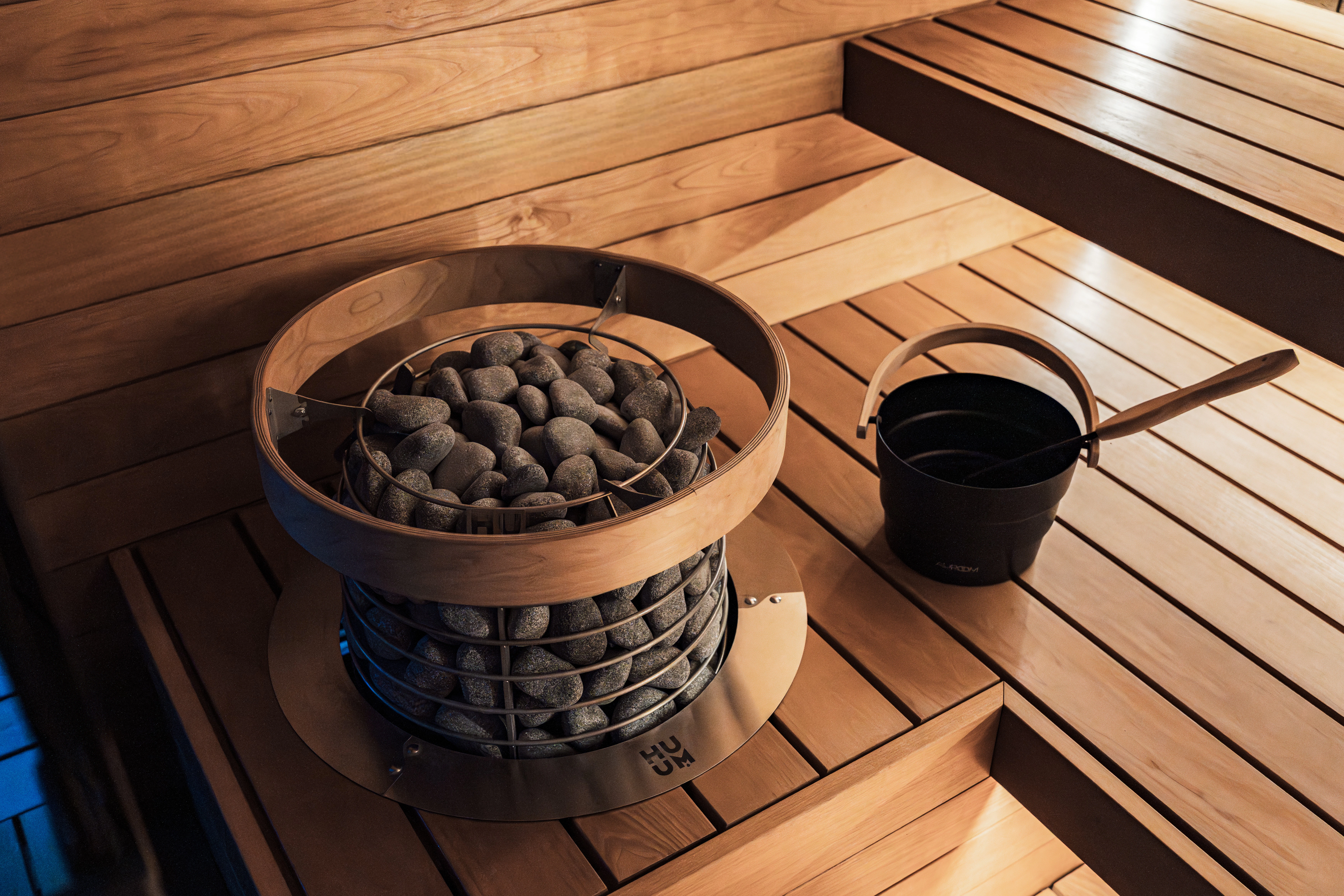 A wooden sauna with a heater and bucket.