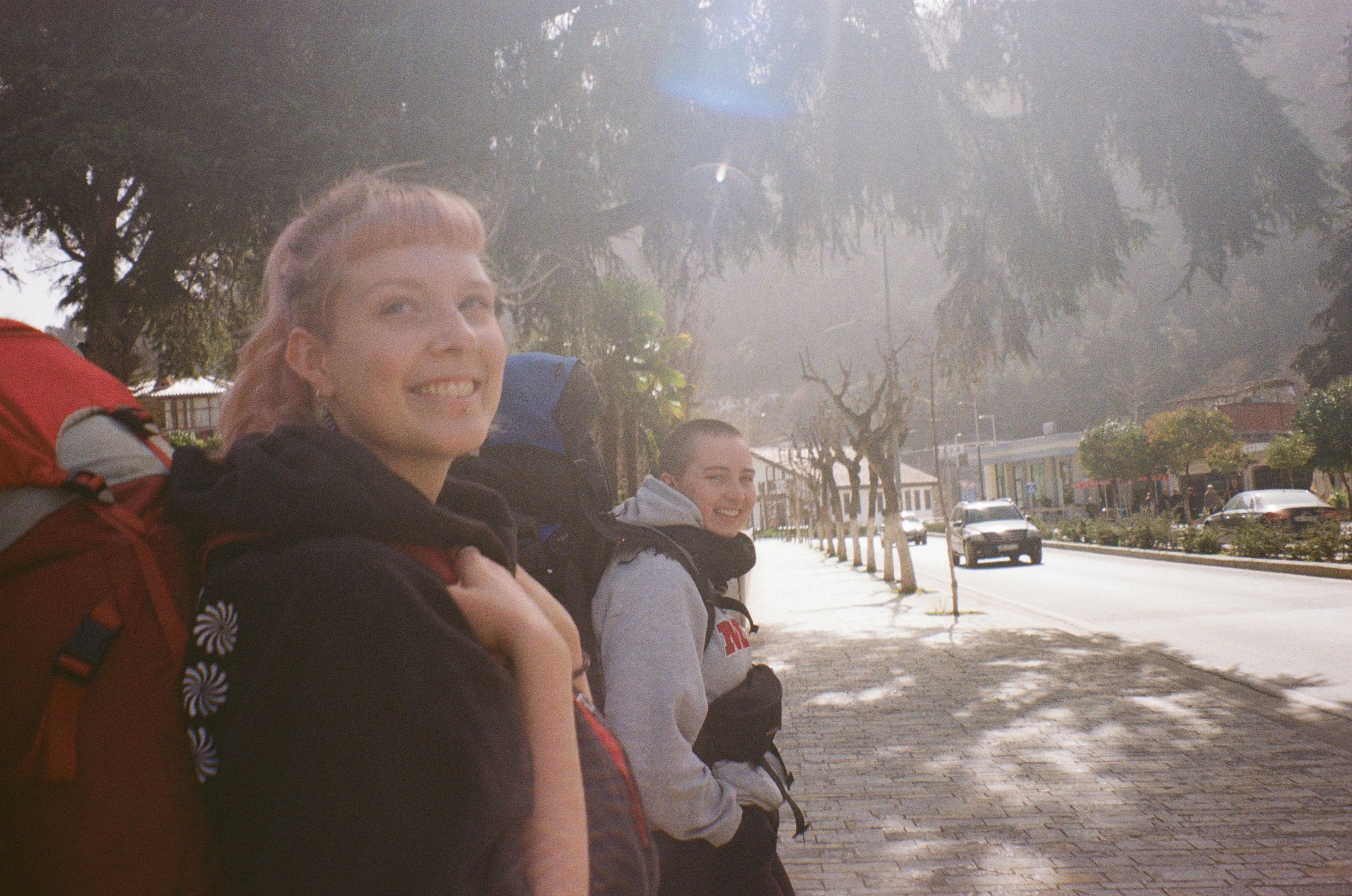 two girls with backpacks walking down the street