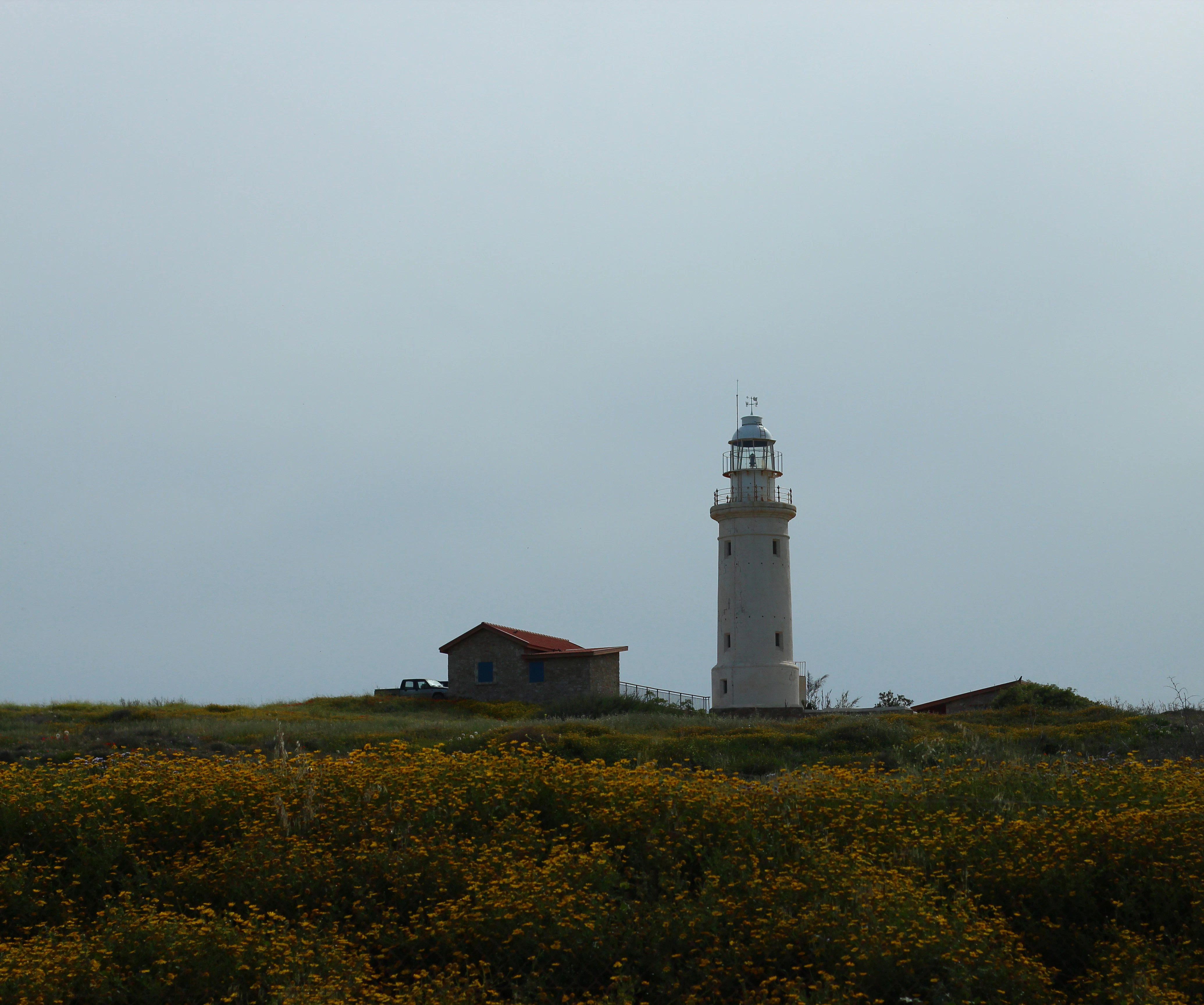 a lighthouse on top of a grassy hill