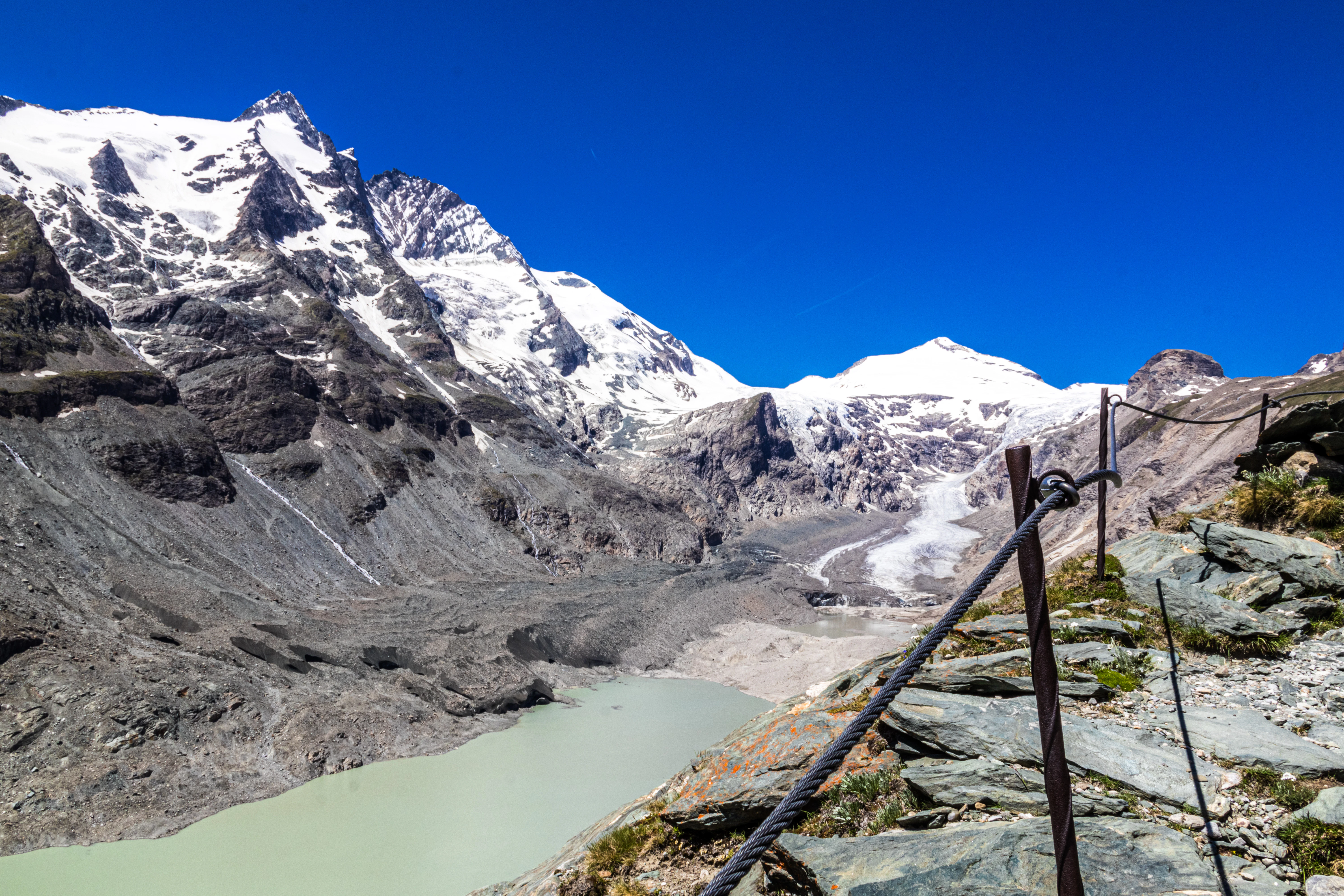 Snow-capped mountains overlook a pale green lake.