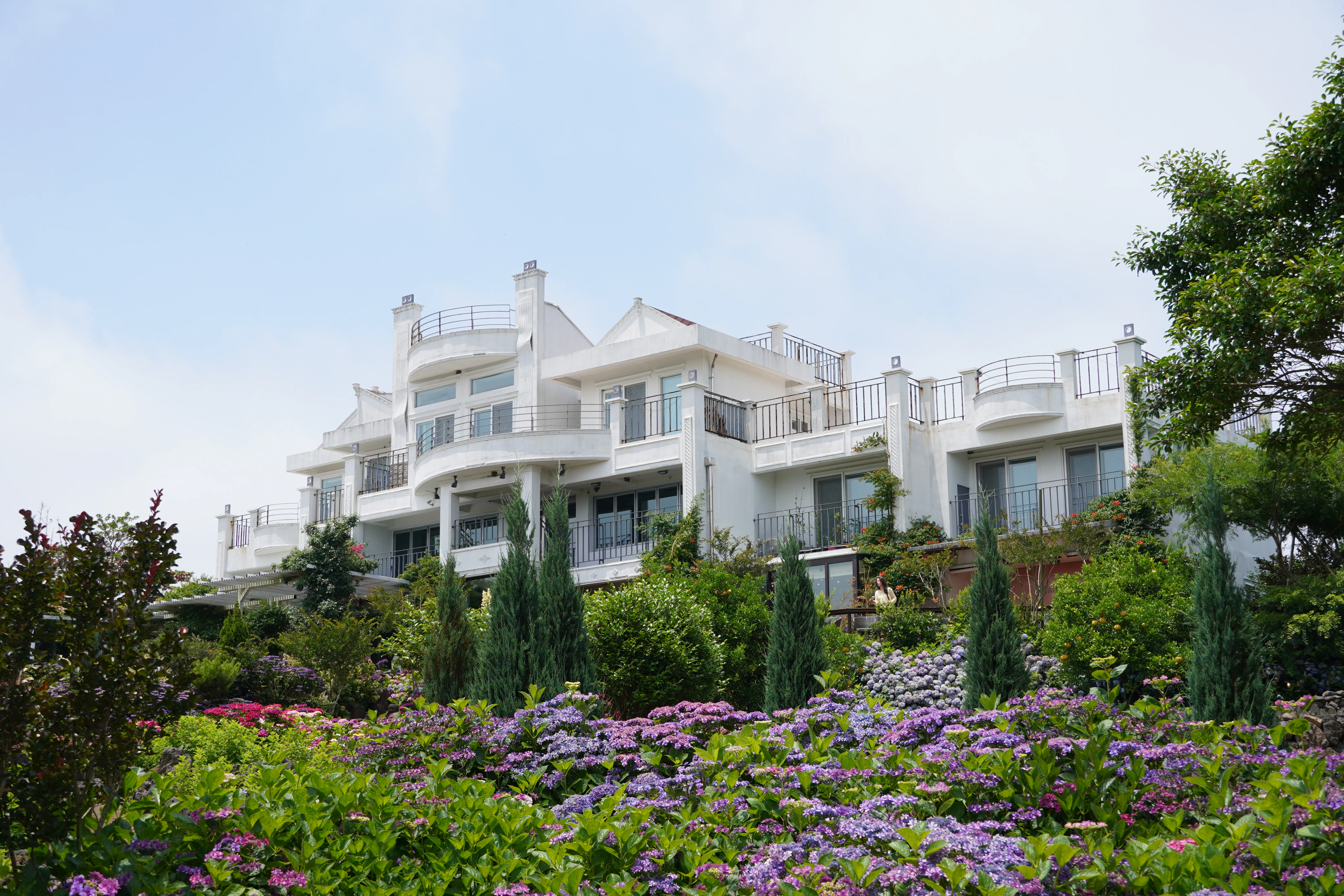 Large white mansion surrounded by lush gardens.
